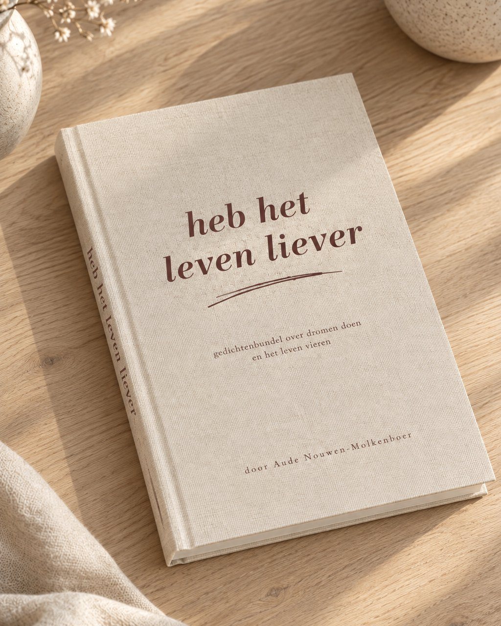 De linnen hardcover bundel Heb het leven liever van Aude Nouwen-Molkenboer op een houten tafel