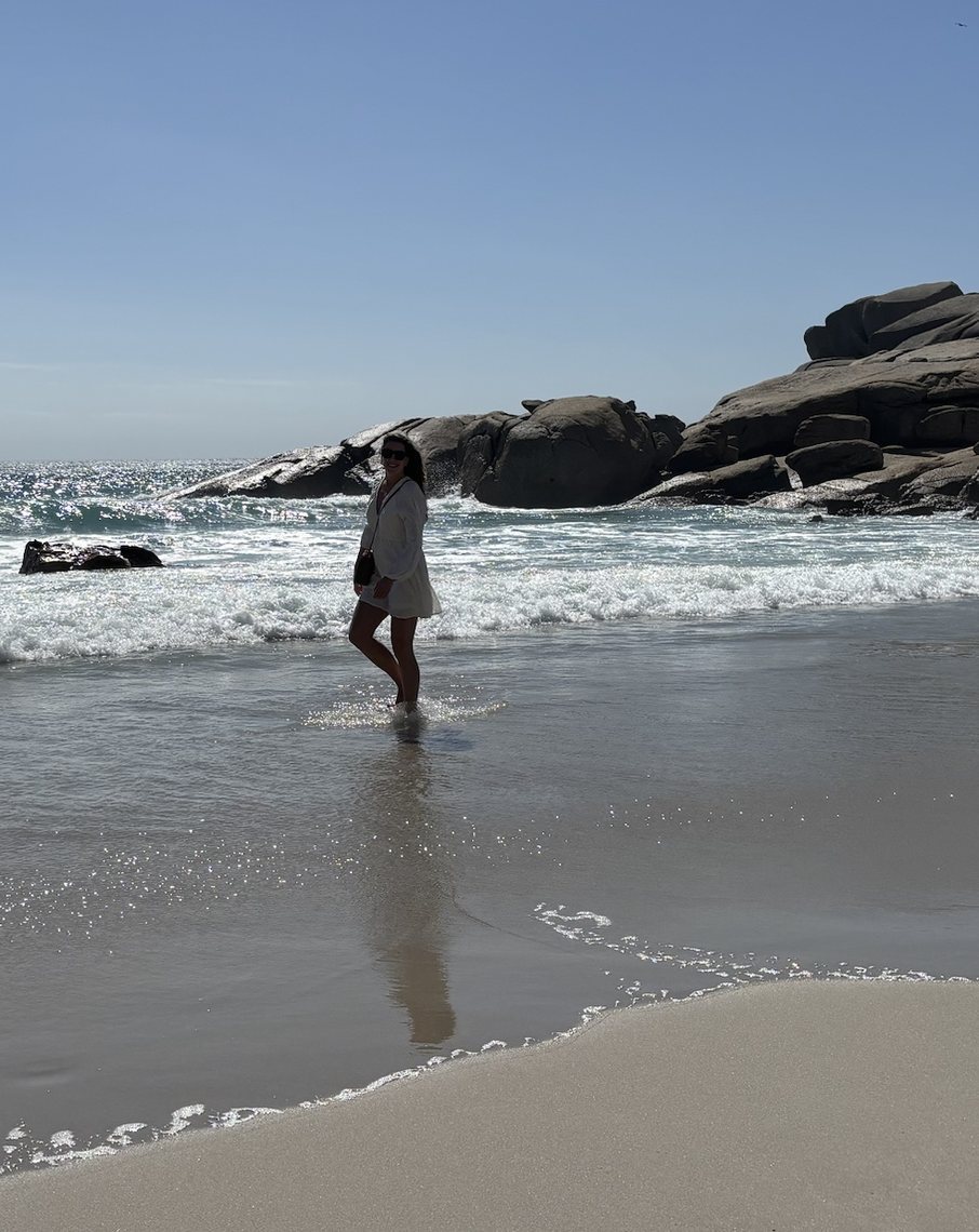 Aude loopt door de branding op een strand met grote rotsen